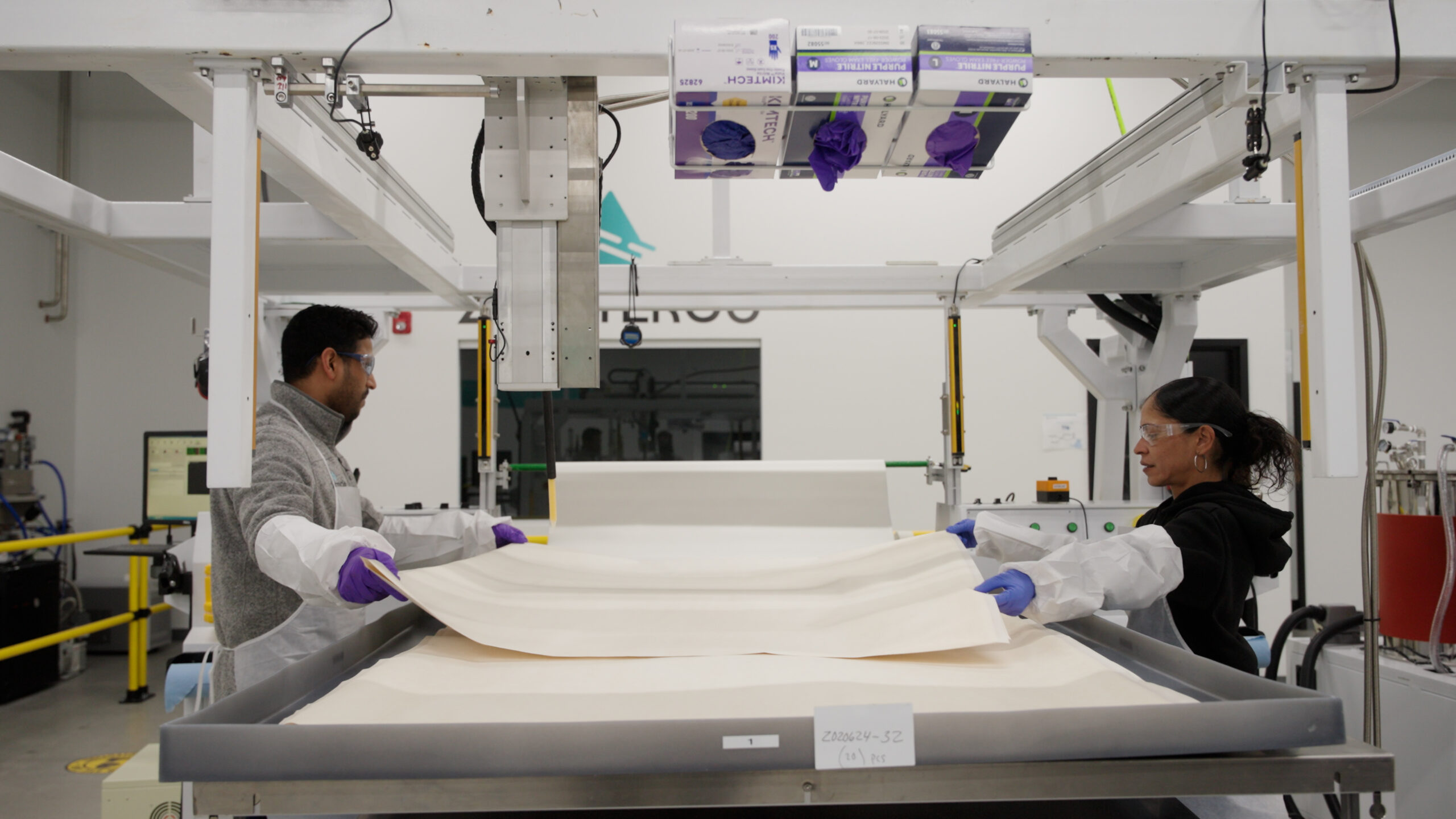 Two ZwitterCo employees by membrane table working to prep membrane in manufacturing process.