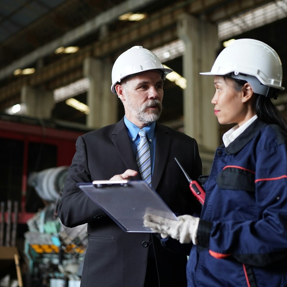 Factory manager and female engineer in factory and inspecting factory in industry plant background.