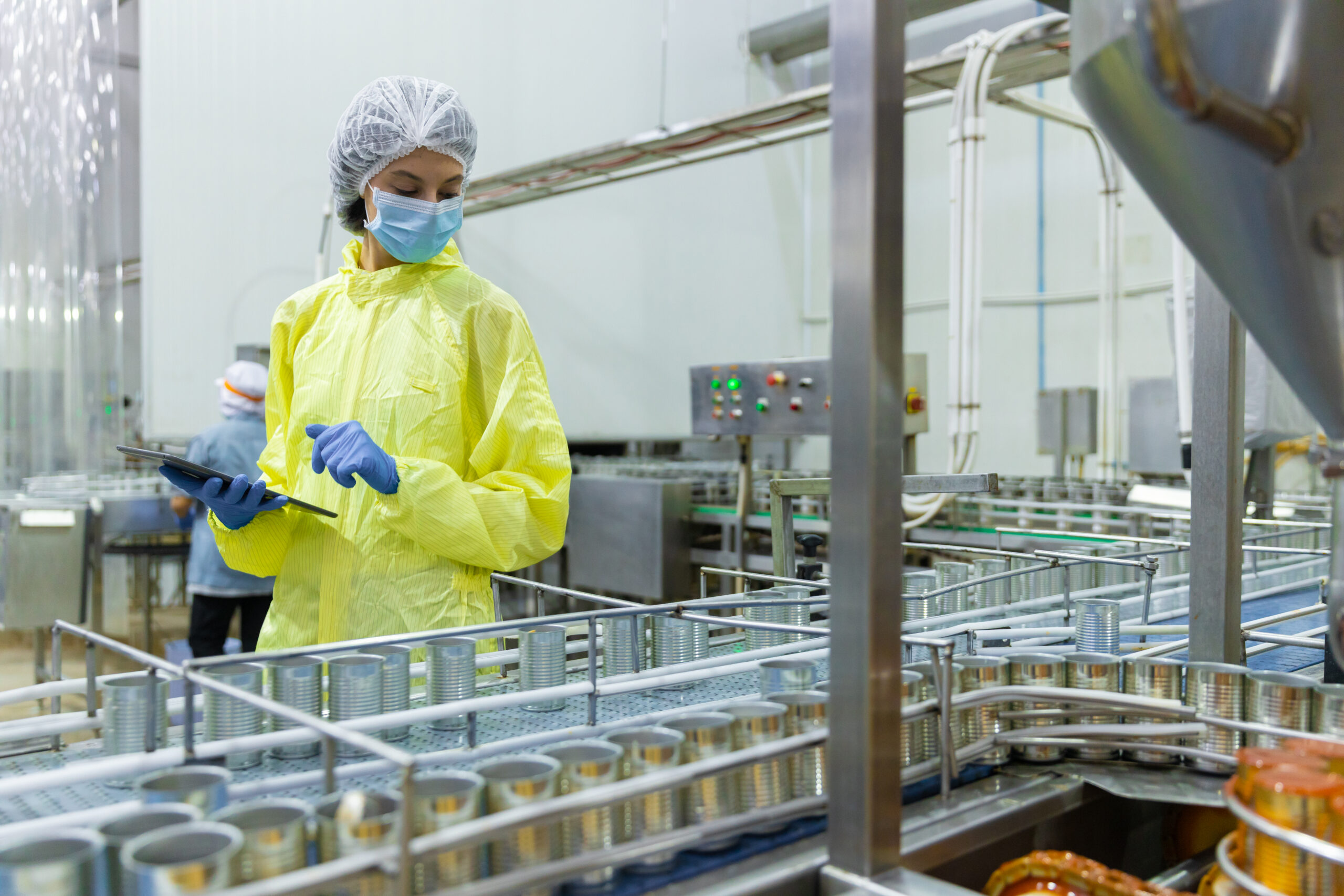 food and beverage processing wastewater reuse Quality control inspectors reviewing canned fish production in seafood factory. Workers using tablet monitor food processing, packaging operations, hygiene standards