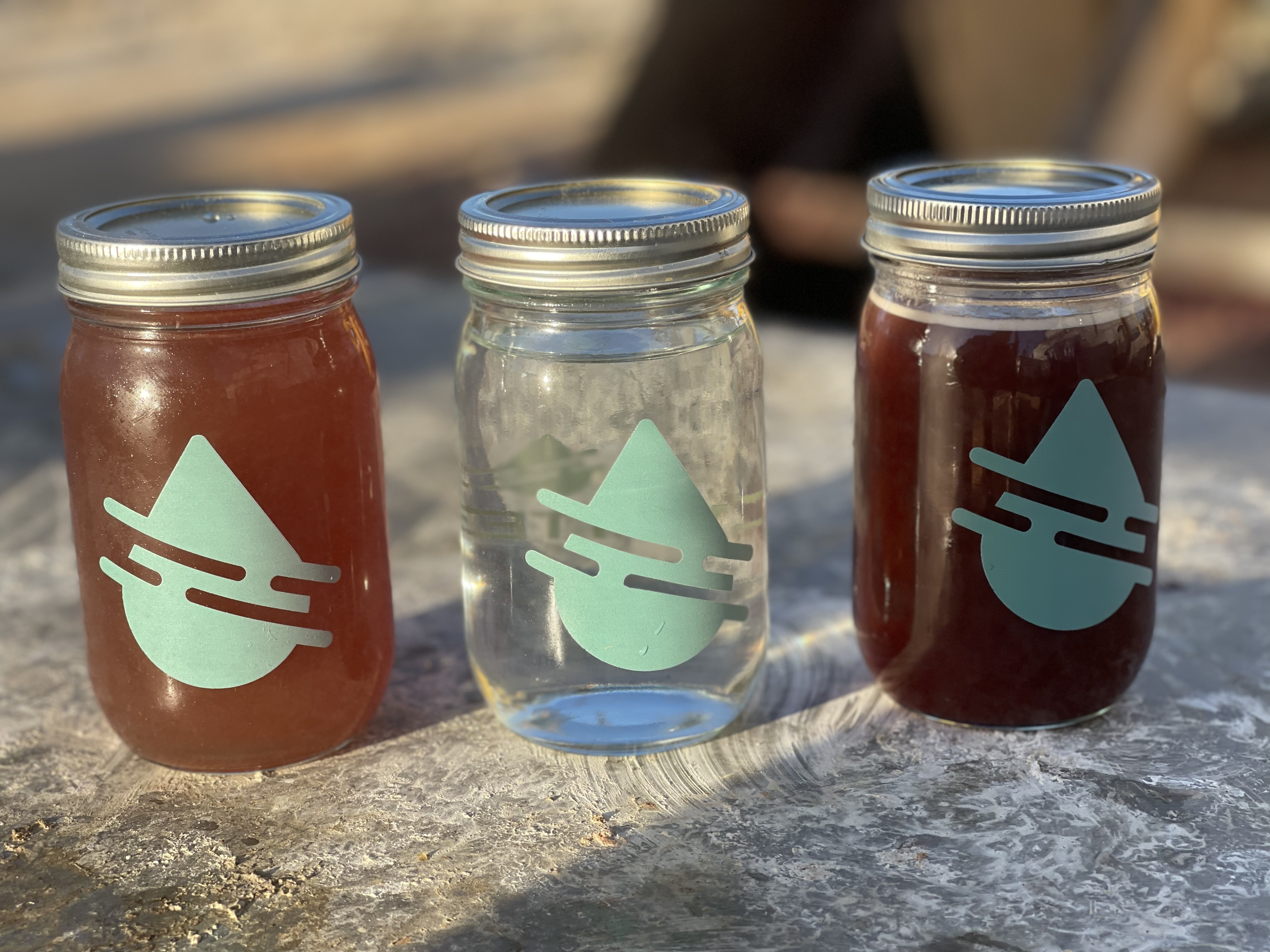 picture showing three jars with liquid of differing colors - medium red feed stream, clean water for reuse, dark concentrate stream